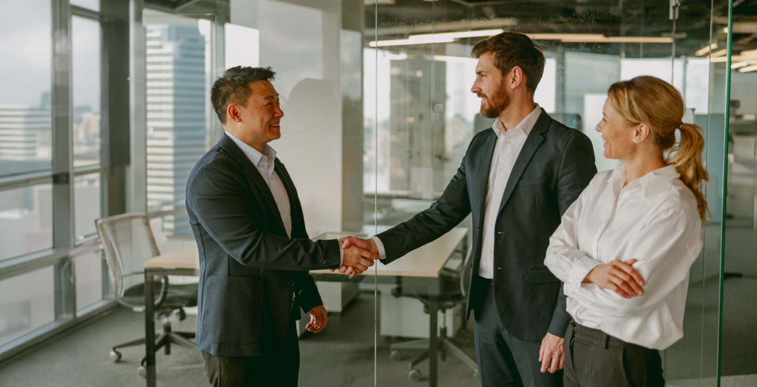 Business professionals are actively engaging in a handshake meeting held in a contemporary office environment